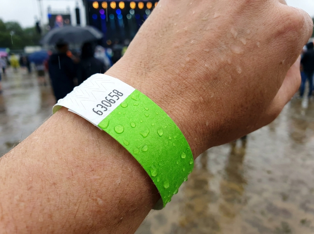 ID wristband worn on a wrist in the rain at an outdoor festival illustrating its resistance to water and moisture