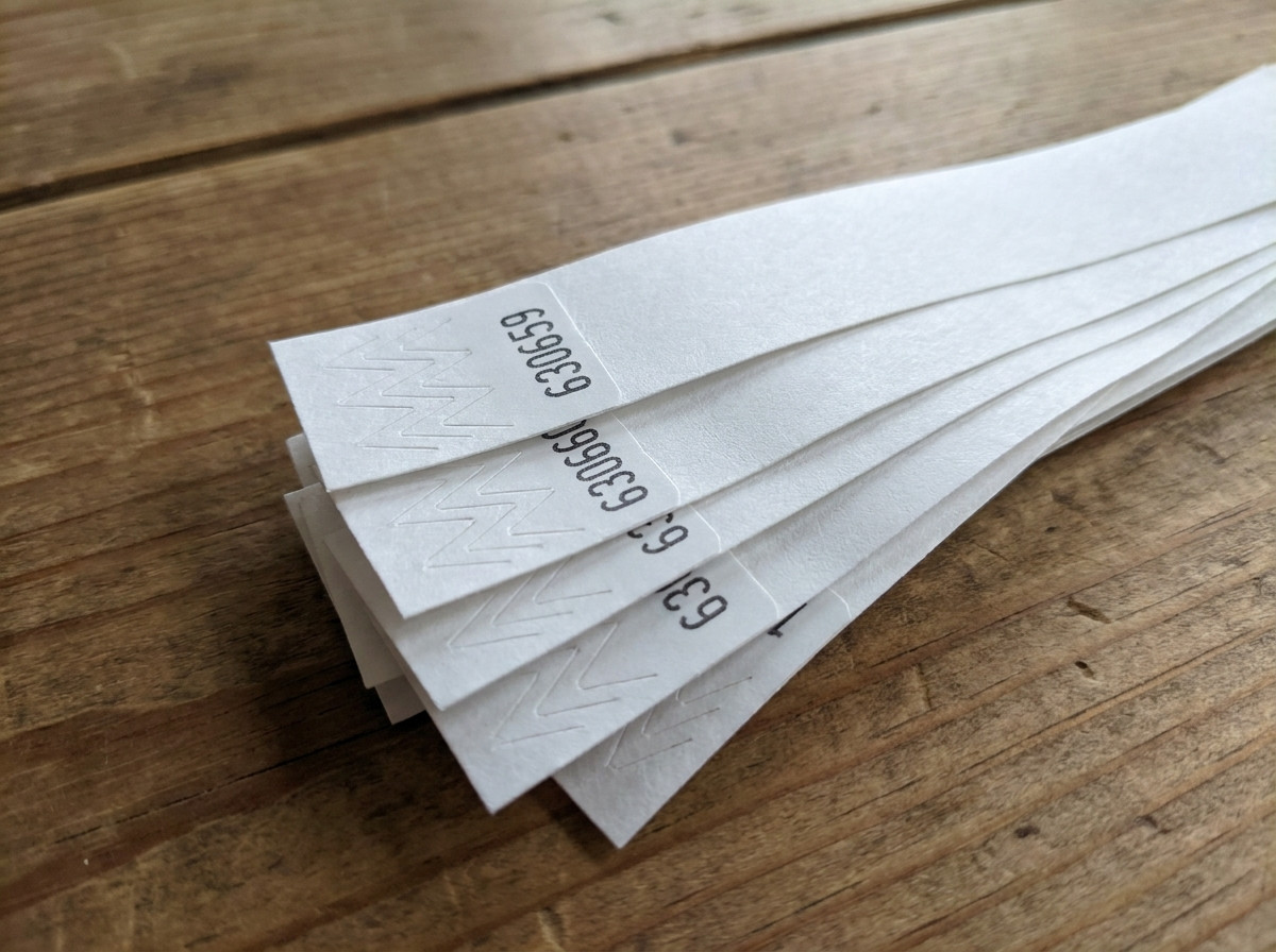 Close-up of Tyvek wristbands with sequential black printed numbering, fanned out on an access control table at an event